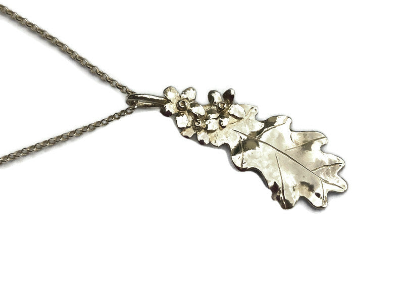 silver oak and flower pendant necklace on white background