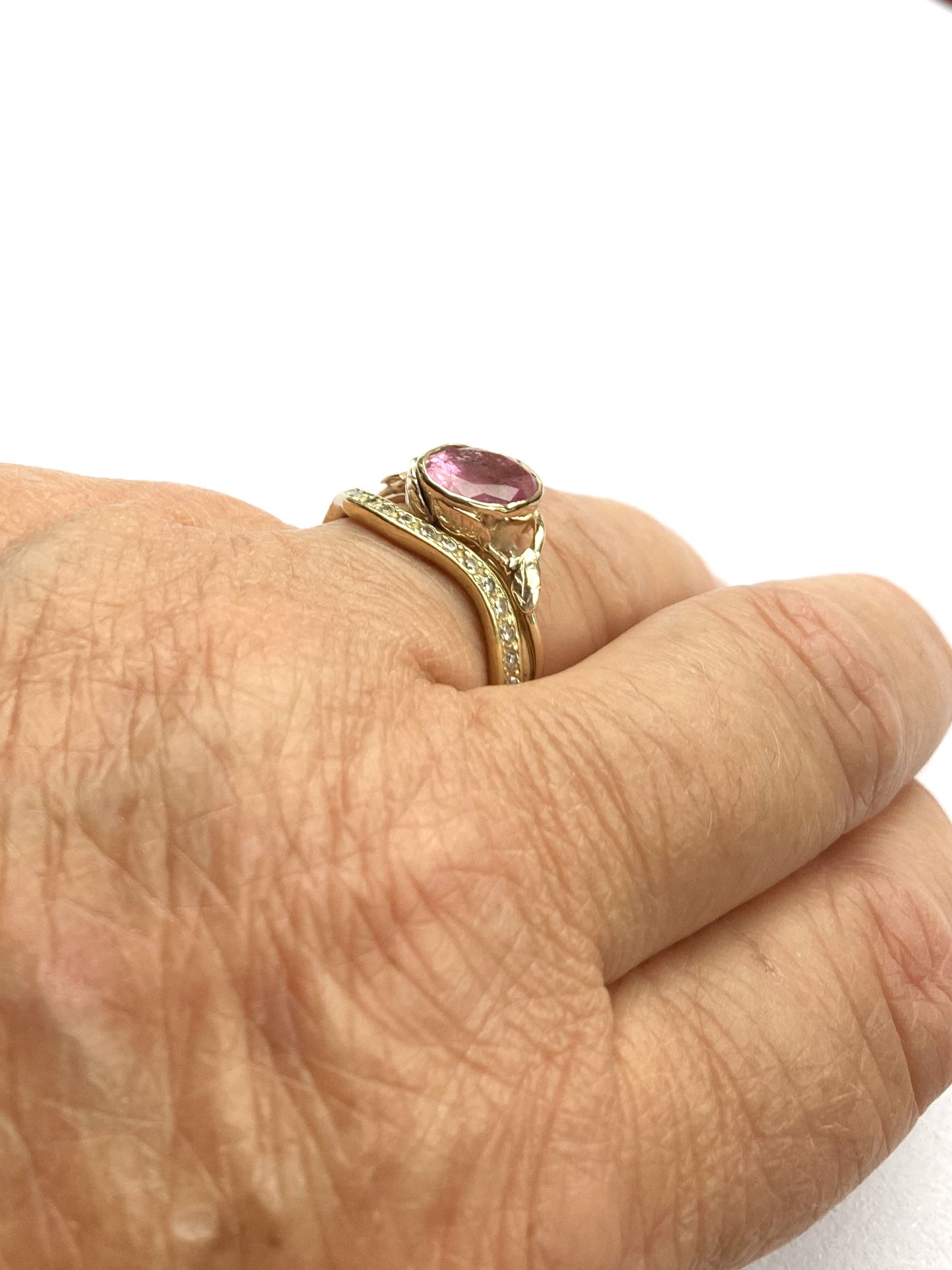 two gold rings on hand, one with large oval pink stone