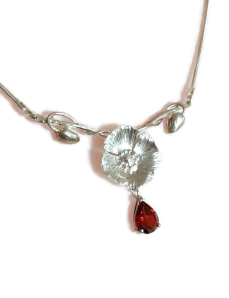 hand forged poppy and bud art nouveau style necklace with hanging garnet drop, by Kim Styles Jewellery, on white background