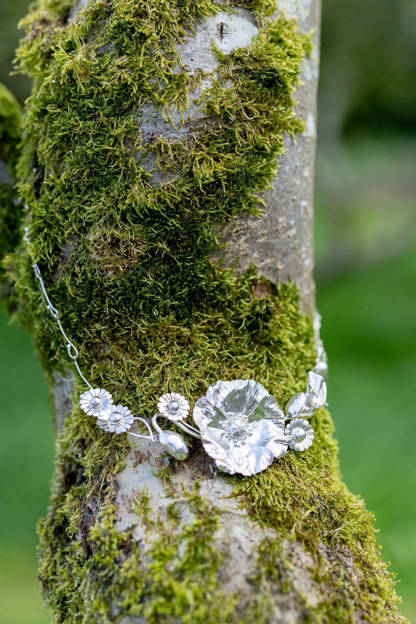 large hammer texture poppy and daisy necklace on mossy tree