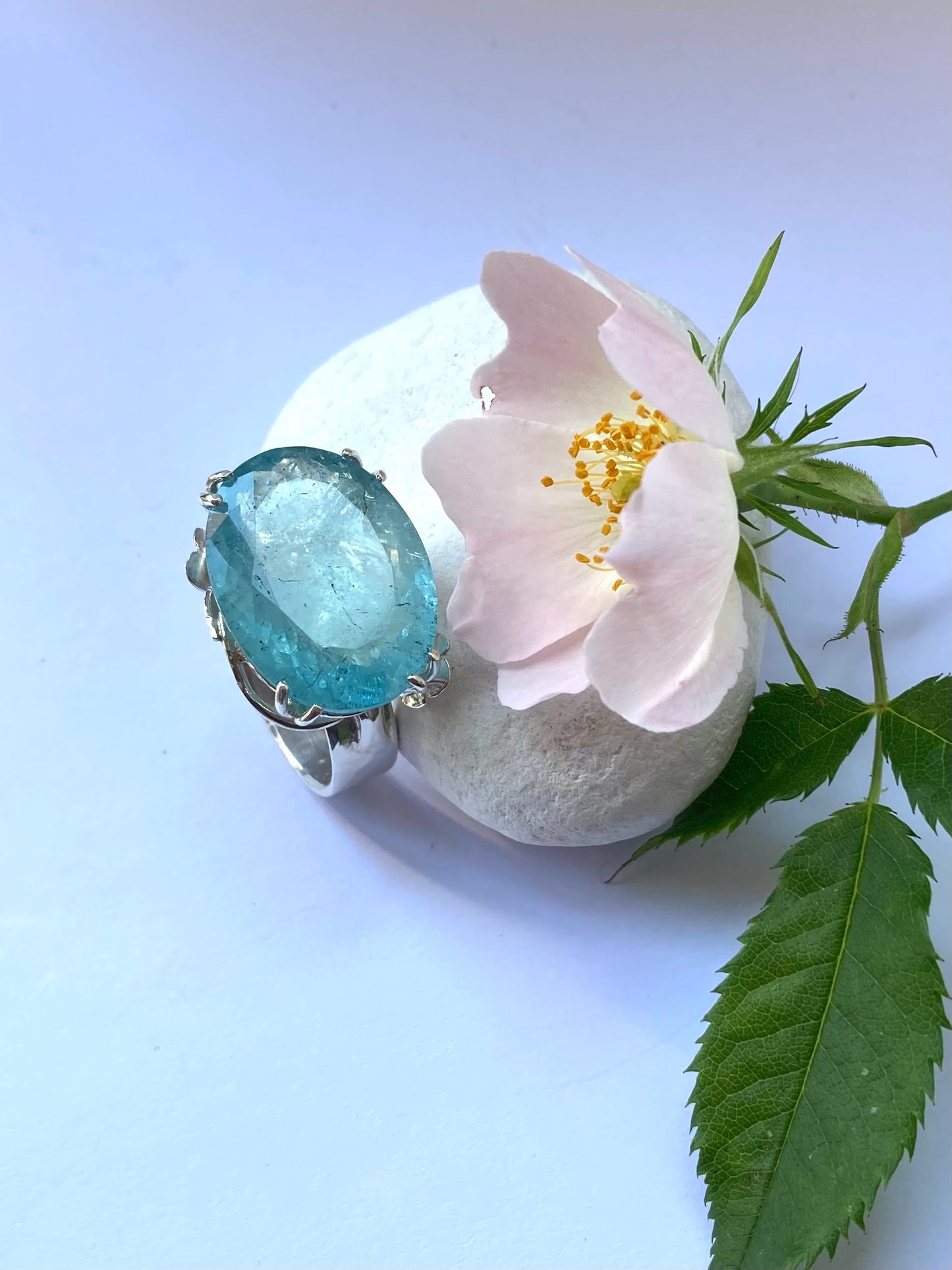 oval blue aquamarine cocktail ring with white pebble and real wild rose with green leaves