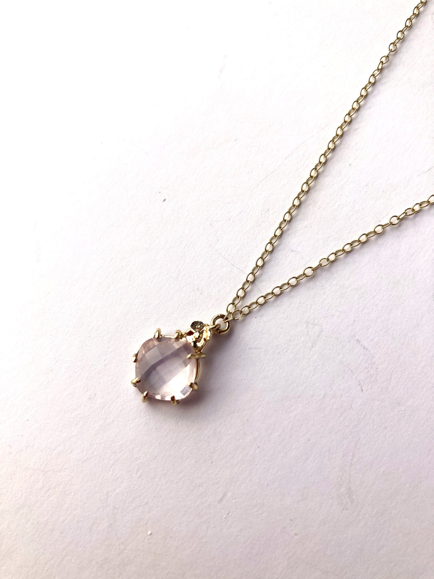 gold pendant and chain with pale pink rose quartz gemstone, on grey background