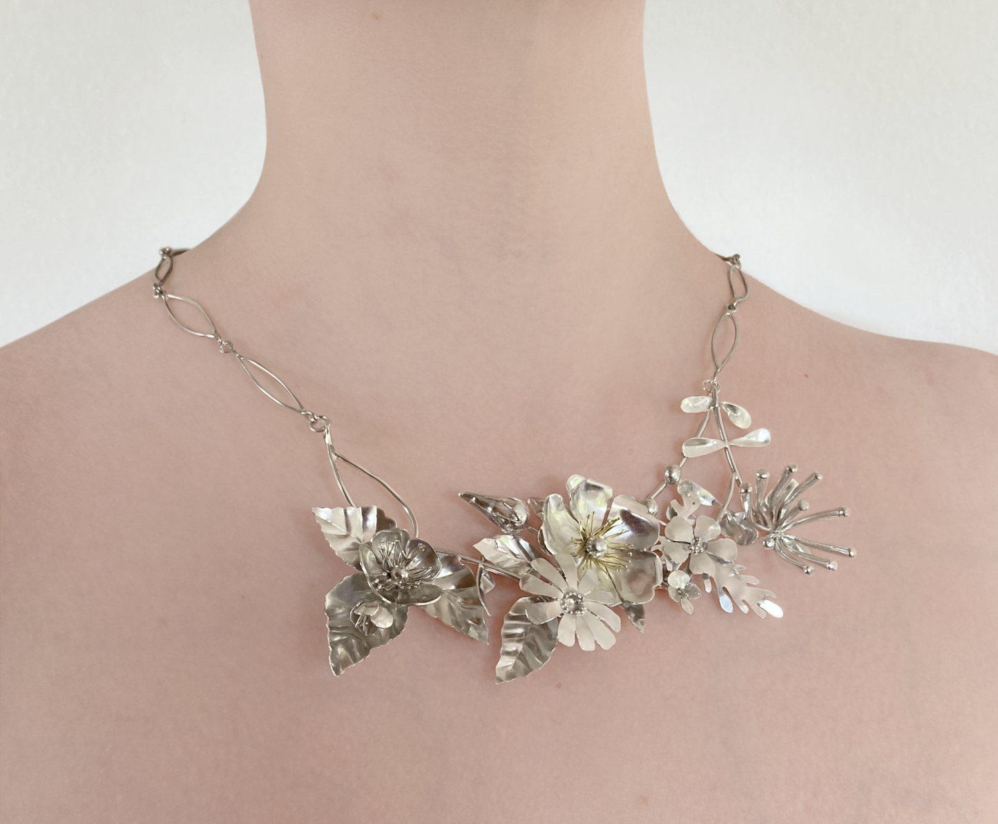 exuberant floral hedgerow necklace with honeysuckle and wild flowers in  sterling silver , on woman's neck