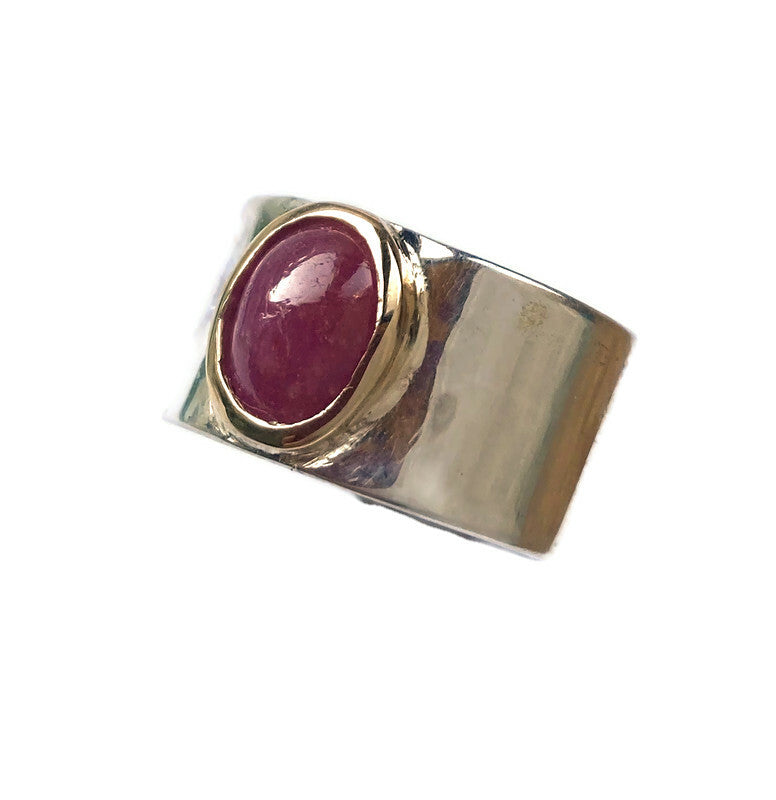 chunky wide silver band ring with large oval cabochon red ruby in rub over yellow gold setting, on white background