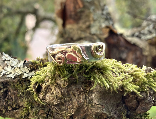 Wide wedding band in white and yellow gold with leaf detail on moss