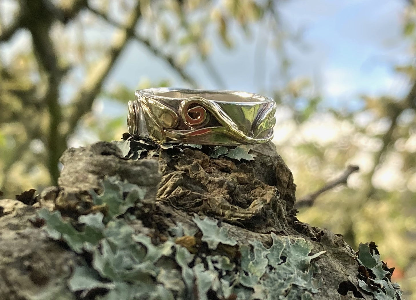 chunky two colour gold ring with scroll and leaf detail, on moss