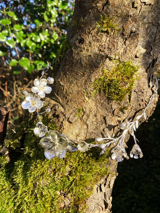 dainty floral necklace of life size handmade silver flowers, looped on a tree