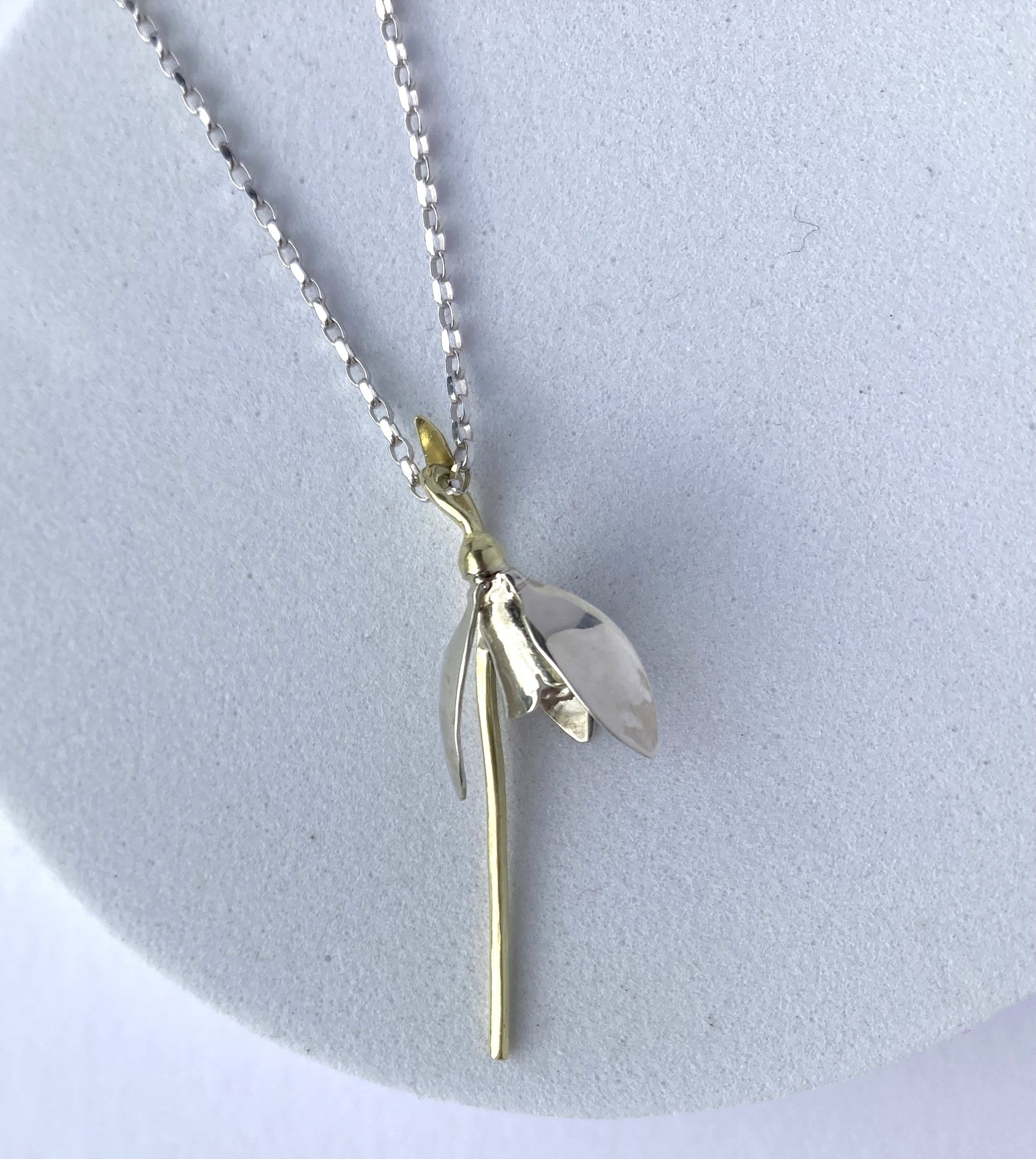 botanical snowdrop pendant hand made in white and green gold by Kim-Styles-Jewellery, on grey plinth