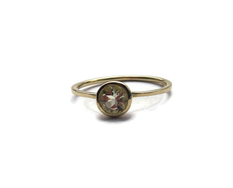 slim yelow gold solitaire ring set with pale green beryl gemstone in rub over setting, on white background