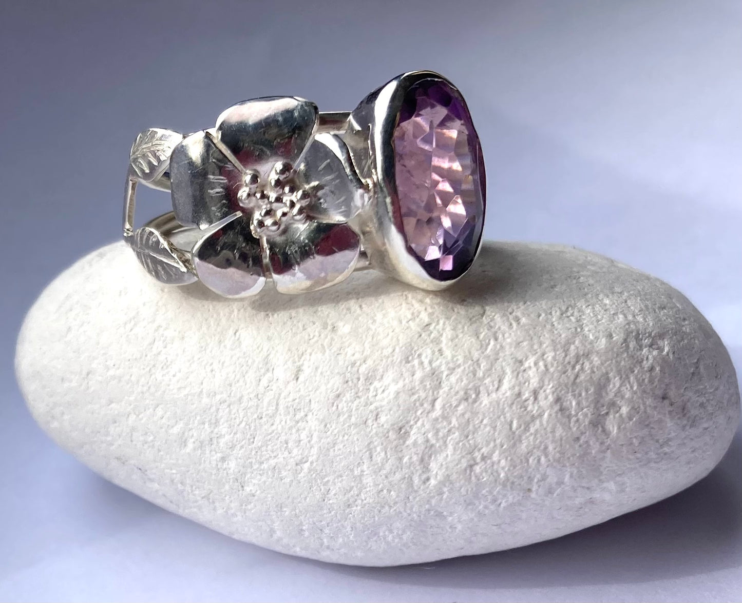 silver rose and leaf ring with large oval amethyst sitting on white pebble