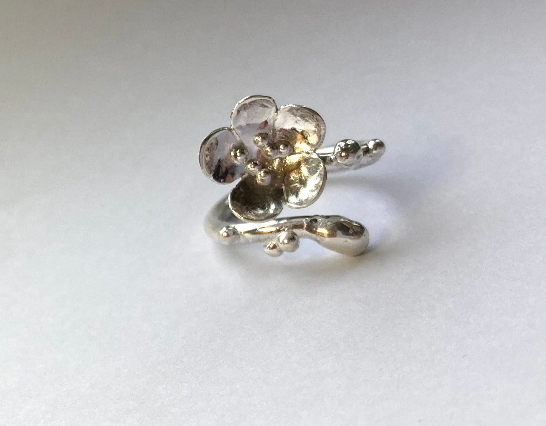 single flower handmade silver ring, on grey background