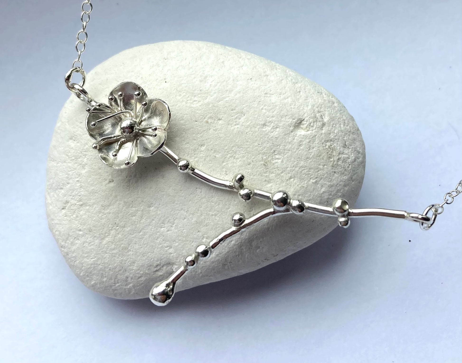 hand forged floral spring necklace, on white pebble