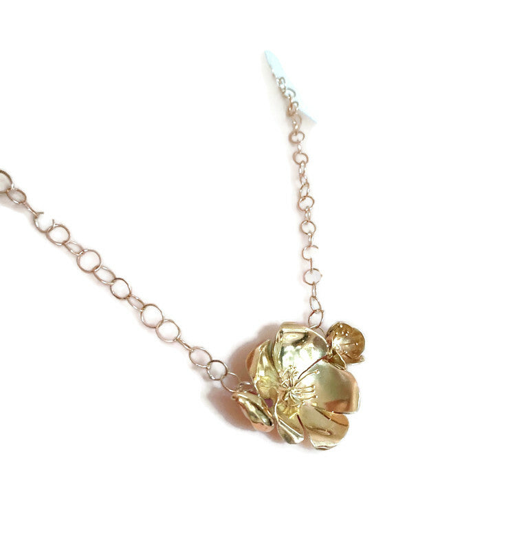 large gold rose necklace and chain on white background