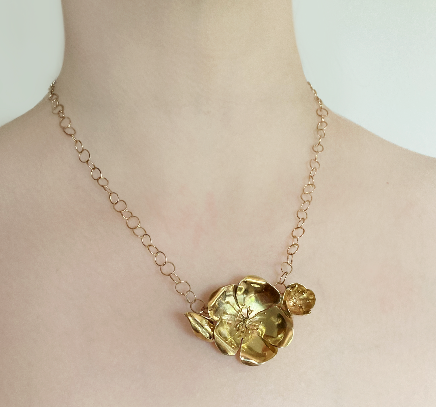 woman's neck wearing big gold rose pendant and open link gold chain