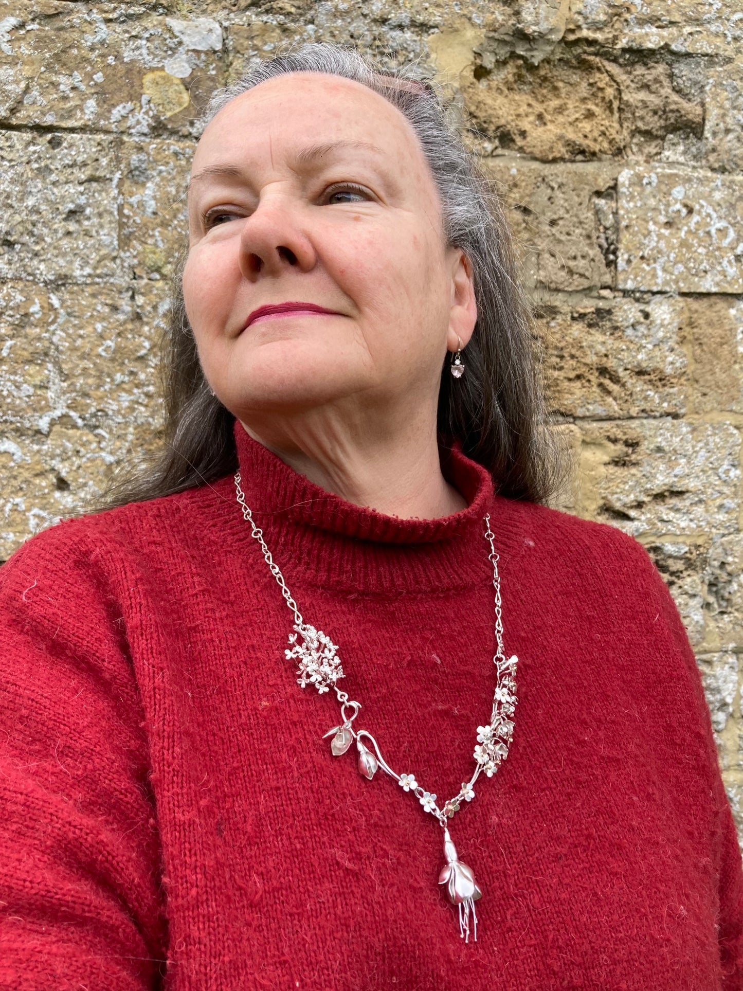 silver botanical flower statement necklace on goldsmith Kim Styles wearing red jumper