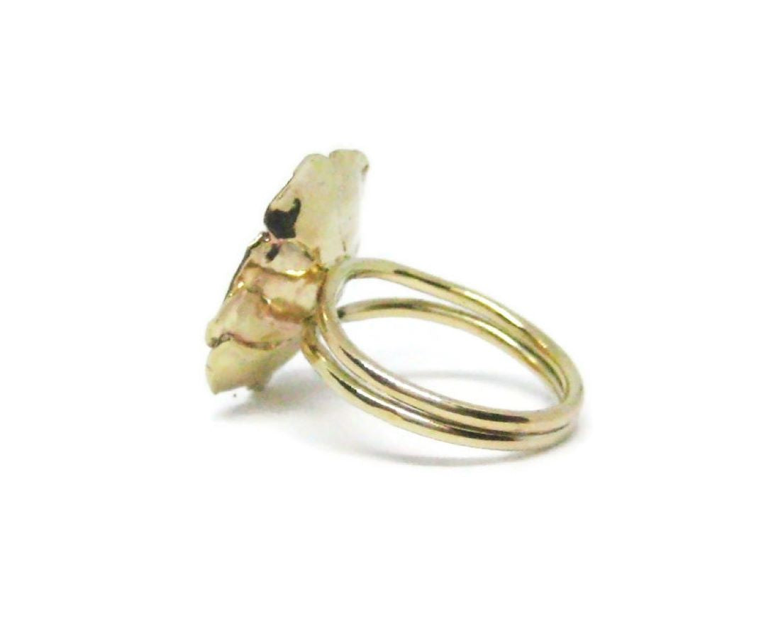 side view of dual shank single gold flower cocktail ring, on white background