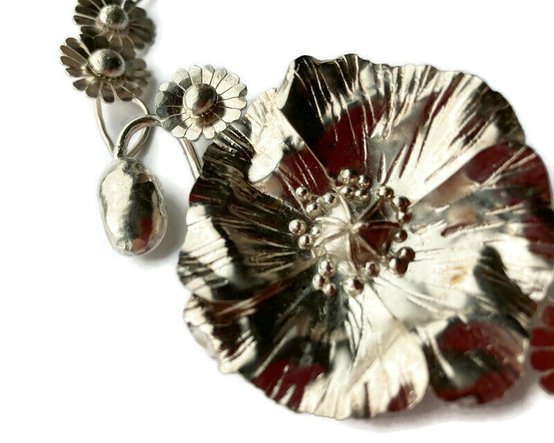 close up detail of hand hammered and forged poppy in sterling silver