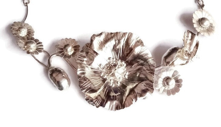 close up of sterling silver hand forged poppy necklace showing all the lifelike crinkles