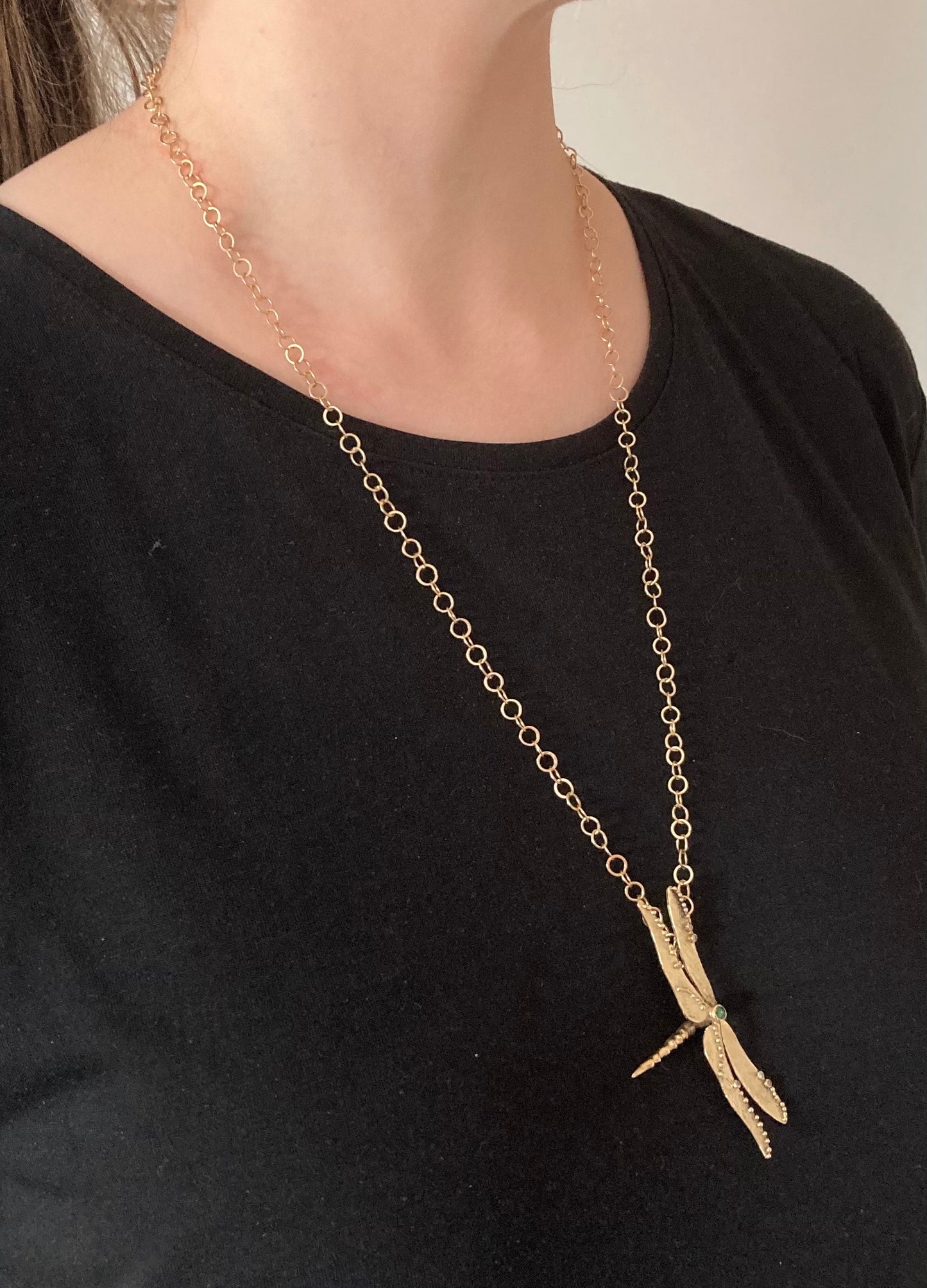 woman in black wearing yellow gold dragonfly pendant on long large link handmade gold chain